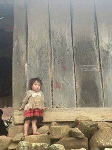 Bé gái người dân tộc đứng một mình trước ngôi nhà gỗ ở Bản Khao Lao, Sơn La, nơi Điểm Trường Khao Lao vừa được xây dựng