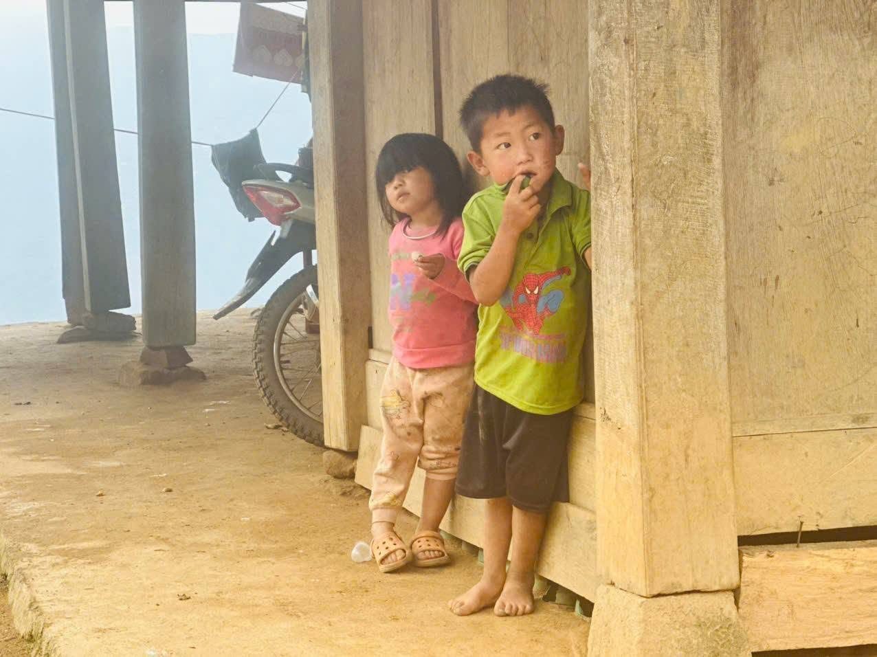 Hai em nhỏ đứng nép bên hiên nhà gỗ tại Khao Lao, Sơn La, khu vực CEO1987 vừa hoàn thành điểm trường mầm non