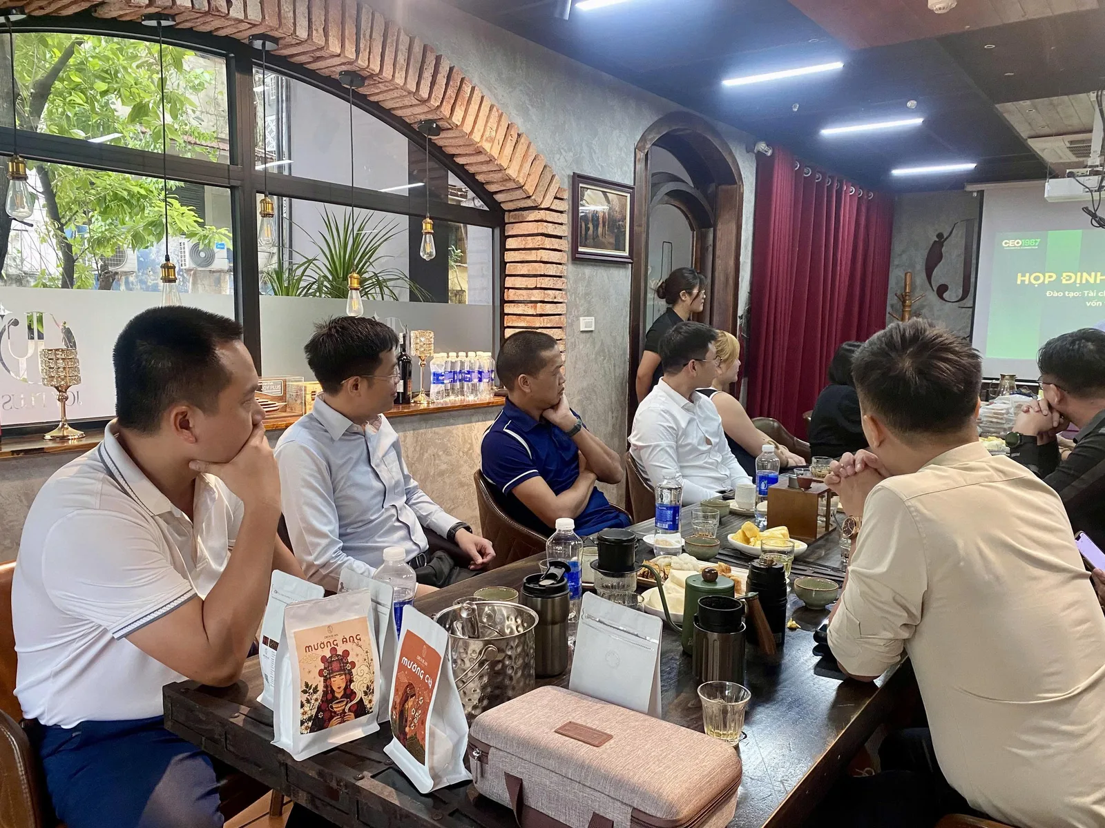 Thành viên CEO1987 theo dõi nội dung họp định kỳ tháng 7, bàn tiệc bày sản phẩm cà phê Mường Ảng, Mường Chà.